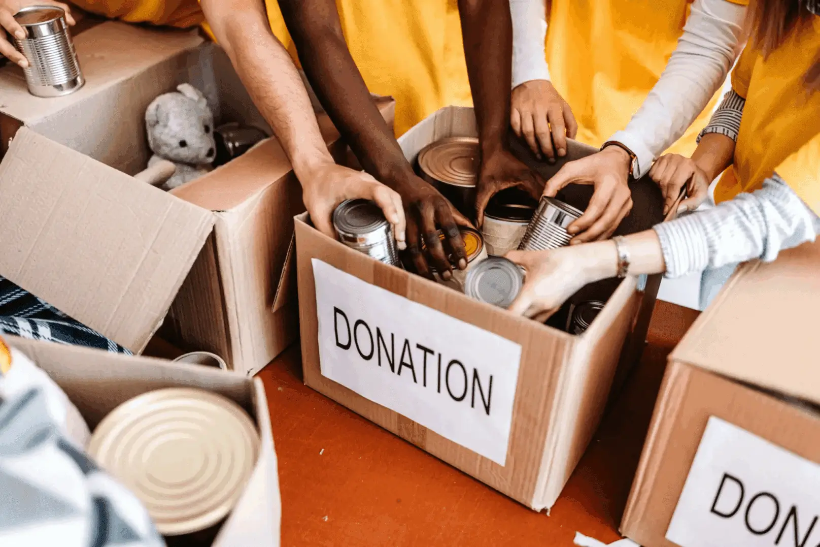 Hands placing canned goods in a donation box labeled 'DONATION'.