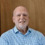 Smiling older man in blue checkered shirt.